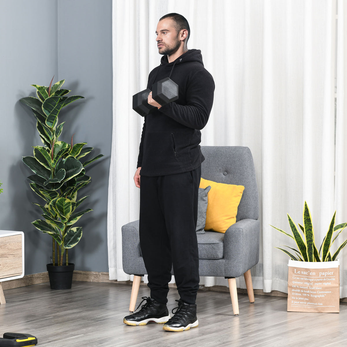 Mann im schwarzen Trainingsanzug beim Krafttraining mit einer 15kg Gusseisen-Kurzhantel.